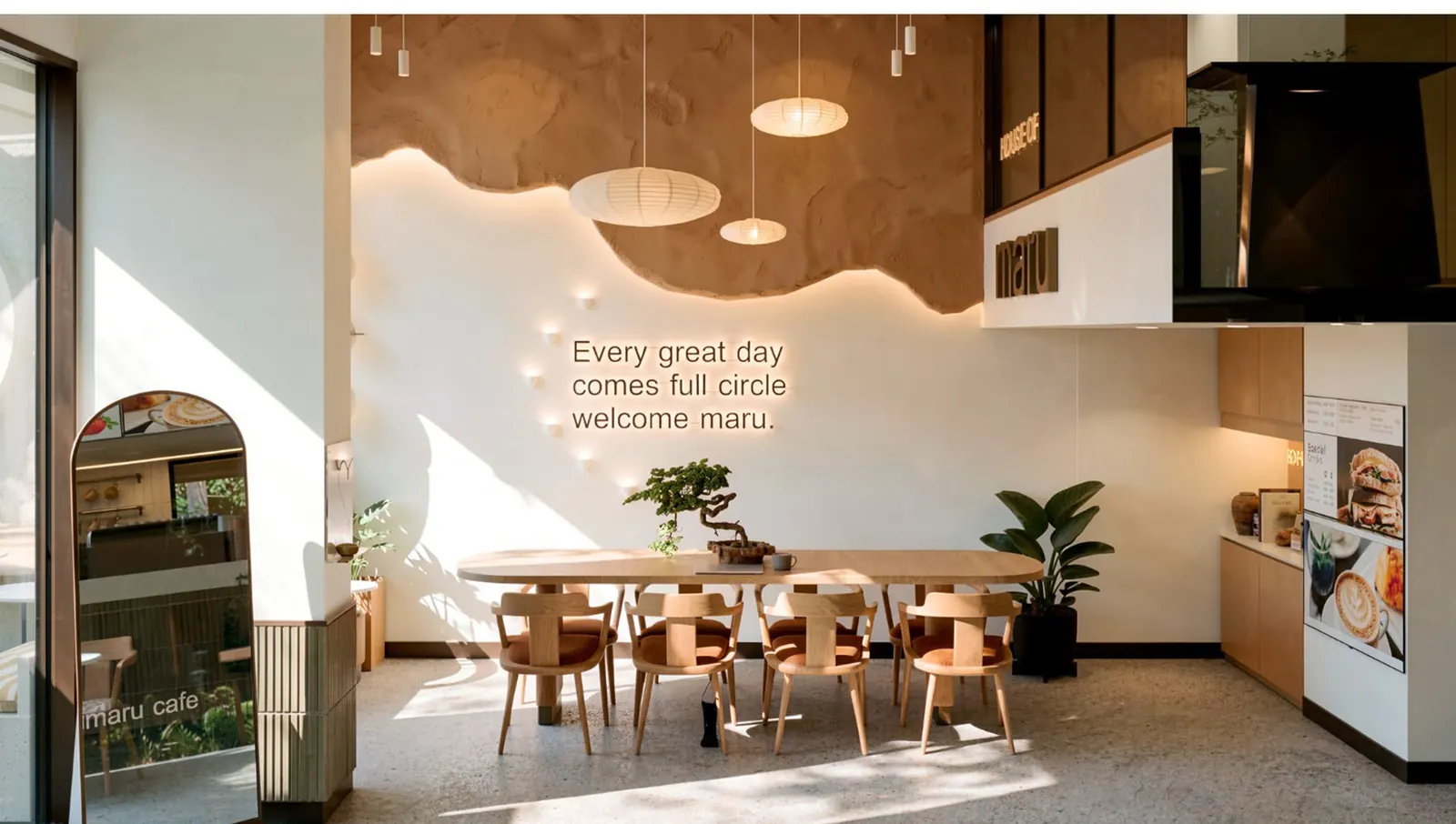 Kafenin duvarında “Every great day comes full circle” yazısı ve uzun ahşap masa